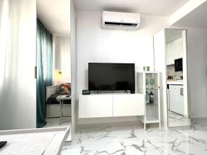 a white living room with a tv on a wall at Apartamento estudio “The mirror” in Torrevieja