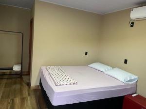ein Schlafzimmer mit einem weißen Bett in einem Zimmer in der Unterkunft Chalé sossego in Pirenópolis