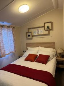 a bedroom with a large bed with two red pillows at Modern & Blissful Beach Park Holiday Home in Dovercourt, Essex, in Parkeston +37 photos