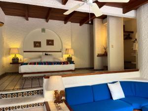 a bedroom with a bed and a blue couch at Villa de La Roca in Zihuatanejo