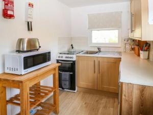 a kitchen with a microwave and a stove at Lletyr Bugail in Caernarfon