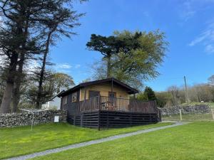 a log cabin with a deck on the grass at Lletyr Bugail in Caernarfon