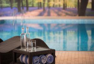 a tray with two bottles and glasses on a table next to a pool at Forest Lodge Hotel in Lyndhurst
