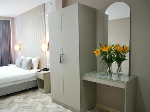 The Roomy Hotel Nişantaşı في إسطنبول: غرفة نوم مع سرير و مزهرية من الزهور على طاولة