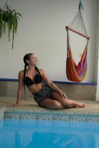 a woman in a bikini sitting next to a swimming pool at Hotel Estación del Sol in Las Núñez +35 photos