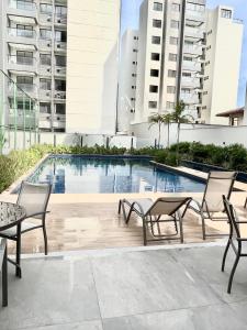 ein Swimmingpool mit Tischen und Stühlen vor Gebäuden in der Unterkunft AP Cantinho baiano Ilhéus Ba in Ilhéus