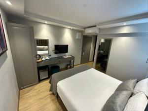 The Roomy Hotel Nişantaşı في إسطنبول: غرفة نوم بسرير ومكتب مع تلفزيون