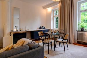 uma sala de estar com um sofá, uma mesa e cadeiras em Apartment mit 2 Schlafzimmern am Bergpark Wilhelmshöhe em Kassel