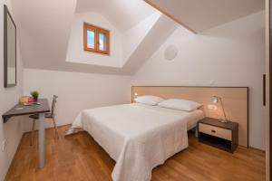 a white bedroom with a bed and a table at Apartments Vallum in Bol