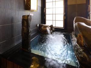 a bath tub with a water fountain in a room at Dormy Inn Express Mikawaanjo in Anjomachi