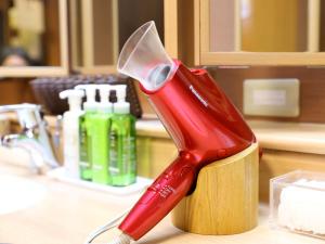 a red electric toothbrush in a holder on a counter at Dormy Inn Express Mikawaanjo in Anjomachi