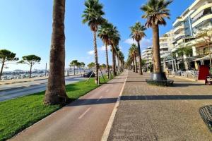 a sidewalk lined with palm trees next to a beach at Diamond Apartment Lungomare Vlore in Vlorë