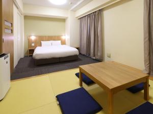 a bedroom with a bed and a desk and a table at Dormy Inn Express Mikawaanjo in Anjomachi