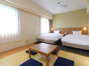 a hotel room with two beds and a table at Dormy Inn Express Mikawaanjo in Anjomachi