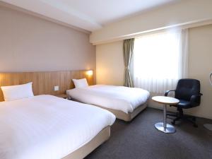 a hotel room with two beds and a chair at Dormy Inn Express Mikawaanjo in Anjomachi