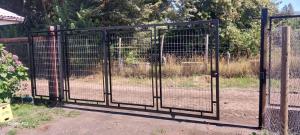 a metal gate with a fence in front of a field at Cabaña Gloria in Coñaripe +4 photos