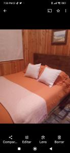 Una foto de una cama con dos almohadas. en Cabaña Gloria, en Coñaripe
