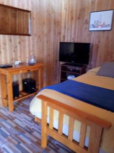 a bedroom with a bed and a flat screen tv at Cabaña Gloria in Coñaripe