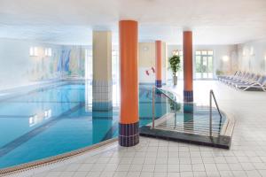 ein großer Pool mit orangefarbenen Säulen in einem Gebäude in der Unterkunft Hotel Ahornhof in Lindberg