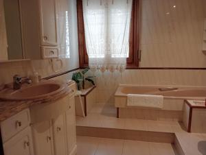 baño con lavabo, bañera y ventana en Alojamientos Zabala en Anguiano, en Anguiano