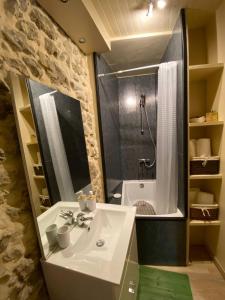 Saint-Geniès-de-Fontedit的住宿－maison de village atypique，浴室配有水槽、淋浴和浴缸。