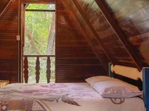 uma cama num quarto de madeira com uma janela em Chalé Floresta Amada em Ouro Preto