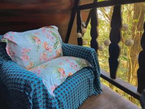 uma cadeira azul com uma almofada sentada num alpendre em Chalé Floresta Amada em Ouro Preto