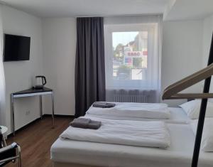 drie bedden in een hotelkamer met een raam bij Am Basler Tor in Grenzach-Wyhlen