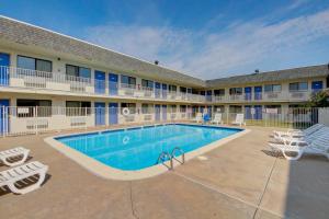 una piscina frente a un hotel con sillas y un edificio en Motel 6-Wichita, KS - AIRPORT en Wichita