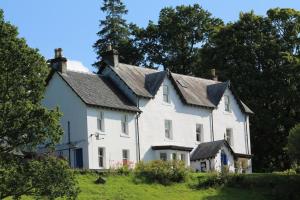 a large white house on a hill with trees at Tirindrish House B&B in Spean Bridge