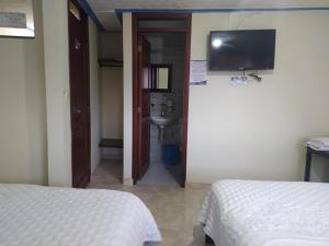 um quarto com 2 camas, um lavatório e uma televisão em Hotel Noche Bella em Ipiales