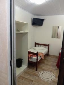 Habitación pequeña con cama y TV. en Pousada Pontal da Armação en Penha