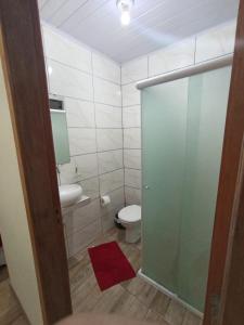 a bathroom with a toilet and a glass shower door at Pousada Pontal da Armação in Penha