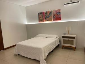 a white bedroom with a bed and a night stand at 3-Bedroom Condo in a Golf Course in Santa Cruz de la Sierra