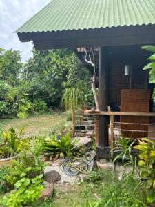 Great House BY Manaeva Lodge في Temae: منزل بسقف أخضر وبعض النباتات