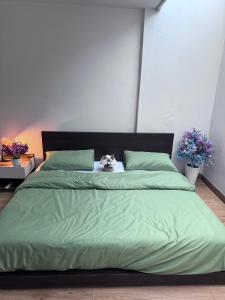 a bed with a green comforter and green pillows at Herb Hop House in Bangkok