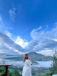 eine Frau in einem weißen Kleid, die ein Foto von einem See macht in der Unterkunft Pinggan glamping ground in Gretek