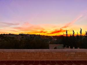 einen Sonnenuntergang über einer Stadt mit Ziegelwand in der Unterkunft QUIET OASIS Luxury Stone Villa with Panoramic Views near Essaouira in Essaouira
