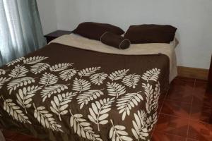 a bed with a brown and white blanket on it at Casa Bonilla El Tirol Heredia CR in Alto del Roble