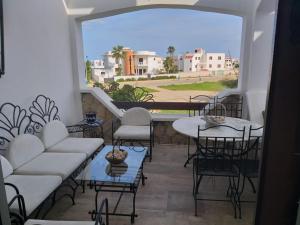 a balcony with tables and chairs and a large window at Appartement moderne à 5 min de la plage in Cabo Negro