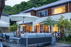 Casa con patio con sillas y sombrilla en Beach Front Litore, en Shimoda