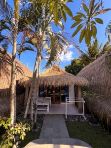 a villa with a thatched roof and palm trees at Coconut Dream Villas in Gili Trawangan
