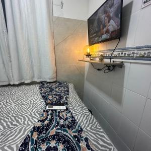 Cama en habitación con TV en la pared en Residencial Napolitan, en Manaus