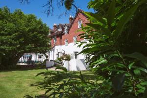 een groot rood bakstenen huis met bomen ervoor bij Moorhill House Bed & Breakfast in Burley