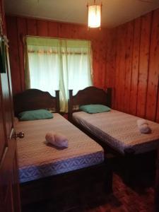 two twin beds in a room with a window at Casa de campo Perlas del Río in Cartago