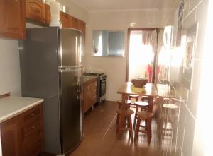 a kitchen with a stainless steel refrigerator and a table at Acolhedor com suíte e wi-fi in Praia Grande
