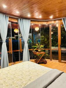 a bedroom with a bed and large glass windows at 6Senses Garden Homestay in Hòa Bình