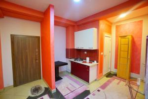a small kitchen with orange walls and a yellow door at Apartman Lazic No2 in Gracanica