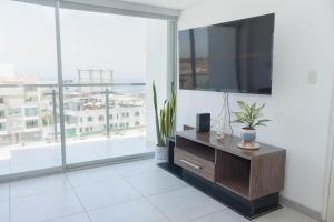 a living room with a tv and a large window at Amplio Duplex Huanchaco - Vista al Mar y Ascensor in Trujillo