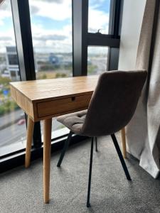 a wooden desk with a chair in front of a window at Rooftop Residence in Auckland